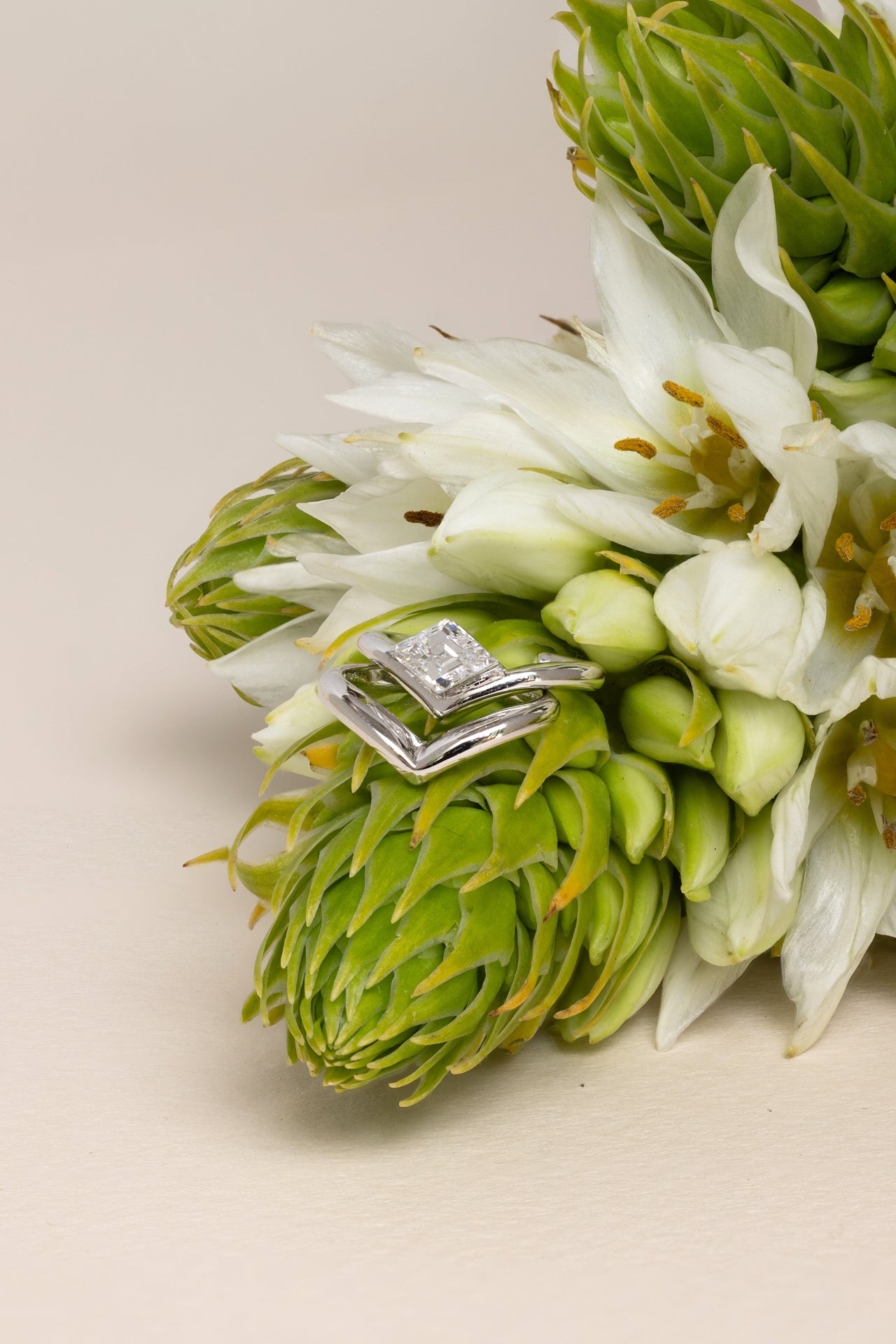 18k white gold V shaped ear cuff with lozenge step-cut diamond next to 18k white gold V shaped ear cuff